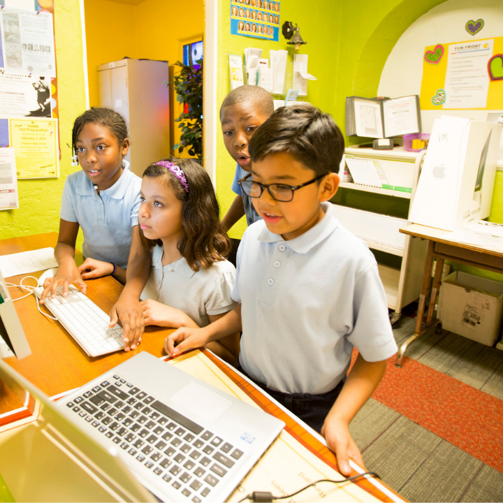 elementary-aged boys and girls looking at a laptop
